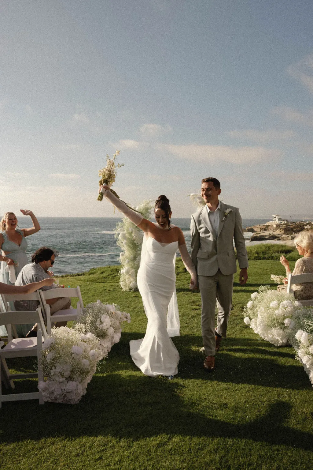 Amber and Tom walk back down the aisle after their Cuvier Park ceremony with the Pacific Ocean behind them.